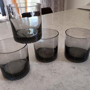 May include: A set of three ceramic mugs with a speckled, cream-colored glaze. Each mug features a different hand-painted floral design in shades of blue, green, and yellow. The mugs have a simple, rounded shape and a comfortable handle.