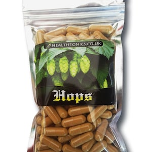 Può includere: Un sacchetto richiudibile argentato pieno di capsule marroni etichettate "Hops" e un'immagine verde di luppolo. Il sacchetto ha anche la scritta "HEALTHTONICS.CO.UK" stampata su di esso.
