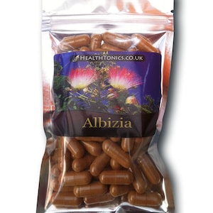 May include: A silver resealable bag filled with brown capsules. The bag has a label with a purple background and a picture of a pink flower. The label says "HEALTHTONICS.CO.UK" and "Albizia".