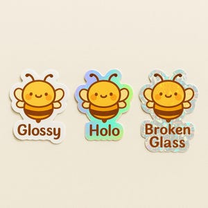 May include: Three bee-themed stickers with different finishes. The first is labeled "Glossy", the second "Holo", and the third "Broken Glass". Each sticker features a smiling cartoon bee in yellow and brown.