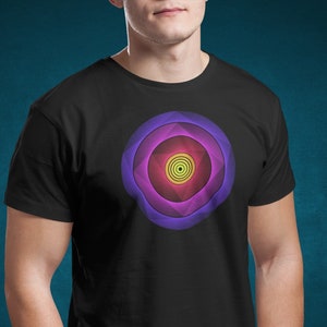 Op de afbeelding: Een zwart T-shirt met een kleurrijk geometrisch ontwerp. Het ontwerp bestaat uit een reeks concentrische cirkels in tinten paars, roze, geel en groen.