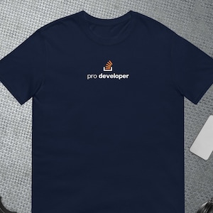 Può includere: Una t-shirt blu navy con un logo bianco che dice "pro developer" e un'icona arancione stilizzata di uno schermo di computer con un frammento di codice all'interno.