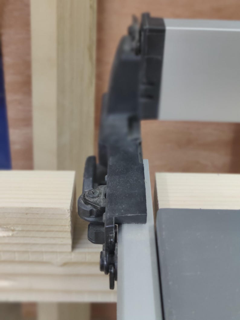 May include: Close-up of a black and silver window sash with a black plastic latch. The sash is attached to a wooden frame.