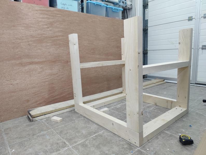 May include: A wooden frame for a shelf unit, constructed from unfinished pine wood. The frame is assembled and ready for shelves to be added.