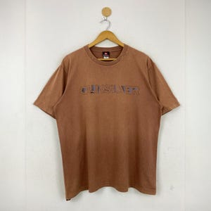 Maglietta vintage Quiksilver taglia XL con grafica retrò anni &#39;90, logo surf Spell Out, maglietta in cotone marrone, abbigliamento da surf unisex, realizzata in Thailandia.