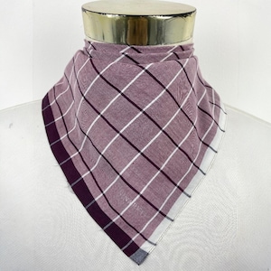 May include: A mauve scarf with a plaid design of white and dark burgundy lines. The scarf is folded and draped over a mannequin. The edges have a dark burgundy border and a white border. The scarf is square in shape.