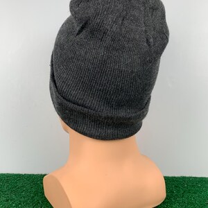 Puede incluir: Un gorro de punto gris. El gorro est&aacute; doblado hacia abajo en el borde.