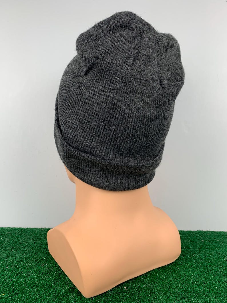 Puede incluir: Un gorro de punto gris. El gorro est&aacute; doblado hacia abajo en el borde.