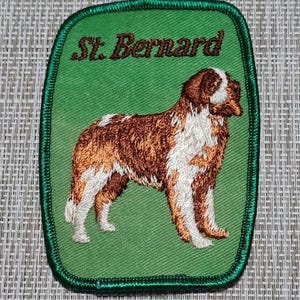 May include: Green embroidered patch with a brown and white St. Bernard dog and the text "St. Bernard" in brown.
