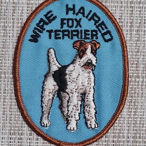 May include: A blue oval embroidered patch with brown stitching. The patch features a wirehaired fox terrier dog and the text "Wirehaired Fox Terrier".