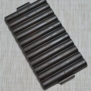 May include: A black cast iron Wagner Ware baking pan with 12 individual molds. The pan is labeled "Wagner Ware, Sidney, Ohio".