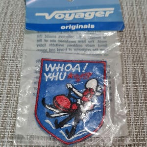 May include: A blue and red embroidered patch with a cartoon figure on a snowmobile. The patch says "WHOA! YHU" in white lettering.