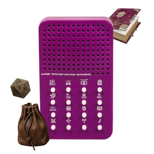 Puede incluir: Una máquina de sonido Game Master morada con botones e iconos blancos, una bolsa de dados de cuero marrón, un dado de veinte caras y un libro burdeos. La máquina de sonido tiene el texto "GAME MASTER SOUND MACHINE" impreso.