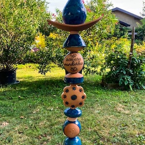 Pode incluir: Um totem de jardim de cerâmica azul e marrom com as palavras "Du bist einfach wunderbar" inscritas em uma das peças.