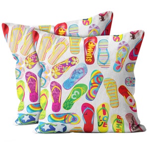 May include: Two white pillowcases with a colorful pattern of flip-flops. The flip-flops are in various colors and patterns, including rainbow, polka dots, stripes, and floral designs. The pillowcases have the words "Summer" and "Love" printed on them.