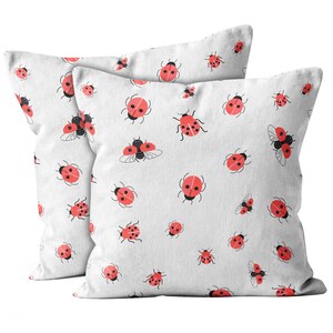May include: Two white pillowcases with a red ladybug pattern. The pillowcases feature a variety of ladybug designs, including ladybugs with wings, ladybugs with spots, and ladybugs with hearts.
