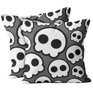 May include: Two gray throw pillows with a white skull pattern. The skulls are outlined in black and have black eyes.
