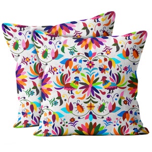 May include: Two colorful throw pillows with a white background and a traditional Mexican folk art design featuring flowers, birds, and insects.