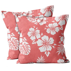 May include: Two coral pink throw pillows with a white hibiscus flower pattern.