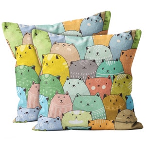 May include: Two colourful pillowcases featuring a pattern of cartoon cats in various colours and poses. The cats are arranged in a random pattern on a light green background.