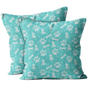 May include: Two turquoise blue throw pillows with a white paw print and bone pattern.