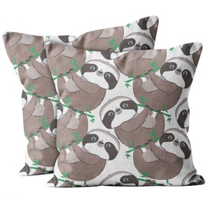 May include: Two square throw pillows with a repeating pattern of cartoon sloths hanging from green branches on a white background. The sloths are brown and have black eye markings.