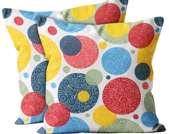 May include: Two decorative throw pillows with a white background and a colorful pattern of large circles with swirls. The circles are in shades of red, yellow, blue, and green.