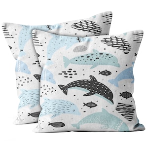 May include: Two white pillowcases with a blue and black dolphin pattern. The dolphins are swimming in a white background with black and blue accents.