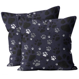 May include: Two navy blue throw pillows with a white and gray paw print pattern.