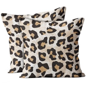 May include: Two throw pillows with a leopard print pattern. The pillows are beige with brown and black spots.