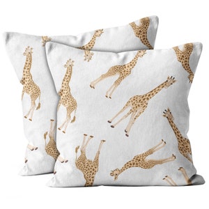 May include: Two white pillowcases with a repeating pattern of brown giraffes printed on them. The giraffes are facing different directions and are in various poses.