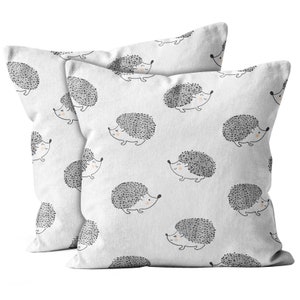 May include: Two white pillowcases with a repeating pattern of gray hedgehogs. The hedgehogs have black eyes and pink noses.