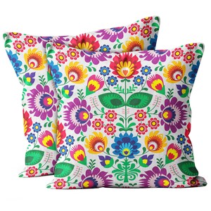 Peut inclure: Deux coussins décoratifs avec un motif floral coloré. Les coussins présentent un fond blanc avec des fleurs rouges, jaunes, bleues, vertes et violettes vives.