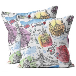May include: Two white throw pillows with a colorful London themed design. The pillows feature landmarks like Big Ben, Tower Bridge, and Westminster Abbey. The design includes the words "England London", "Travel", "Capital", and "United Kingdom".