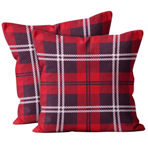 May include: Two red plaid cushions with a traditional tartan design. The cushions display a striking pattern of intersecting white and black lines over a red backdrop, producing a visually appealing effect. The cushions are square-shaped.
