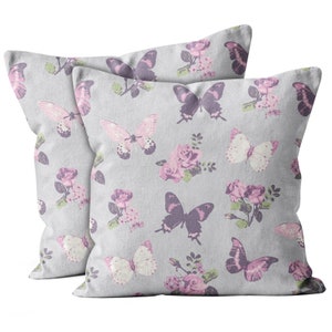 May include: Two gray pillow covers with a butterfly and floral pattern. The pillows feature a light gray background with pink and purple butterflies and roses.