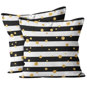 May include: Two square throw pillows with a black and white striped pattern. Gold glitter polka dots are scattered across the surface. The pillows are made of a soft fabric and are designed for decorative use.