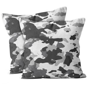 May include: Two gray and white camouflage patterned throw pillows. The pillows are made of a soft, textured fabric.