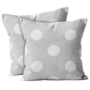 May include: Two gray throw pillows with a white polka dot pattern. The pillows are made of a soft, textured fabric.