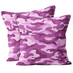 May include: Two pink camouflage patterned throw pillows. The pillows are made of a soft, plush fabric and feature a subtle sheen.