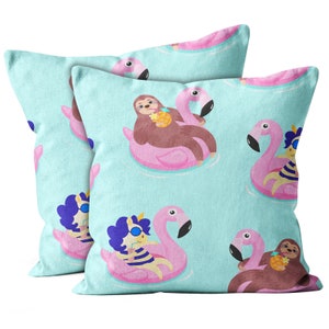 May include: Two square throw pillows with a repeating pattern of cartoon sloths and unicorns floating on pink flamingo pool floats. The background is a light blue color, resembling water. The sloths and unicorns are holding pineapples.