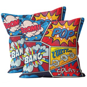 Peut inclure: Deux oreillers bleus, rouges et jaunes avec un motif de bande dessinée représentant les mots "BOOM!" "POP!" "BANG!" "ZZZT!" et "SPLAT!"