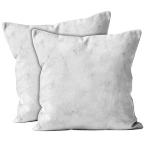 May include: Two white throw pillows with a marble pattern.