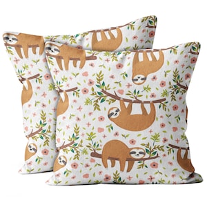 May include: Two white pillowcases with a brown sloth design. The sloths are hanging from branches with pink flowers and green leaves.