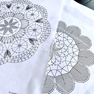 Könnte beinhalten: Zwei Schwarzweiß-Zeichnungen von Spitzenmustern auf weißem Papier. Die Muster sind kreisförmig und weisen komplizierte Designs mit sich wiederholenden Motiven auf. Der Text "MU_BLANKPAGE_ENG_0519" ist in der linken unteren Ecke sichtbar.