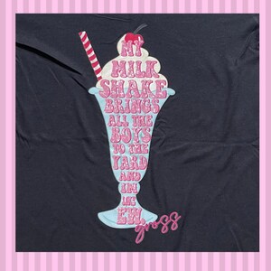 May include: Black t-shirt featuring a pink and blue milkshake graphic. The milkshake graphic has the text "My milkshake brings all the boys to the yard and they like it, ew, gross".