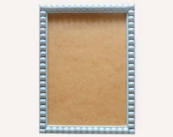 May include: A light blue picture frame with a beaded border. The frame is empty and ready for a photo.