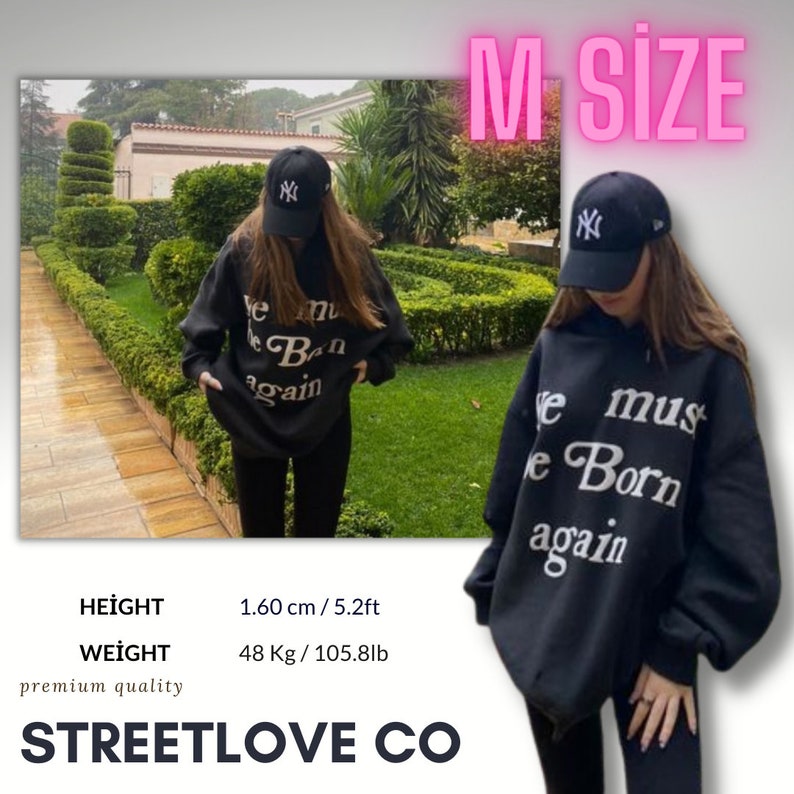 May include: Black hoodie with the text "We must be Born again" in white lettering. The model is wearing a black baseball cap with a white "NY" logo. The text "HEİGHT 1.60 cm / 5.2ft WEİGHT 48 Kg / 105.8lb premium quality STREETLOVE CO" is visible at the bottom of the image.