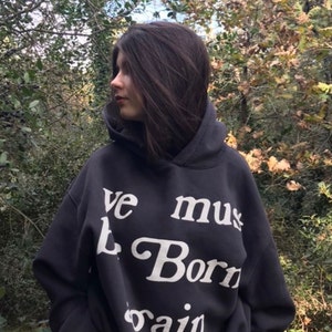 May include: A black hooded sweatshirt with the text "We must be born again" printed in white.