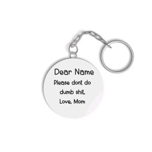 May include: A white keychain with a silver chain and a round tag that says "Dear Name Please don't do dumb shit. Love, Mom."